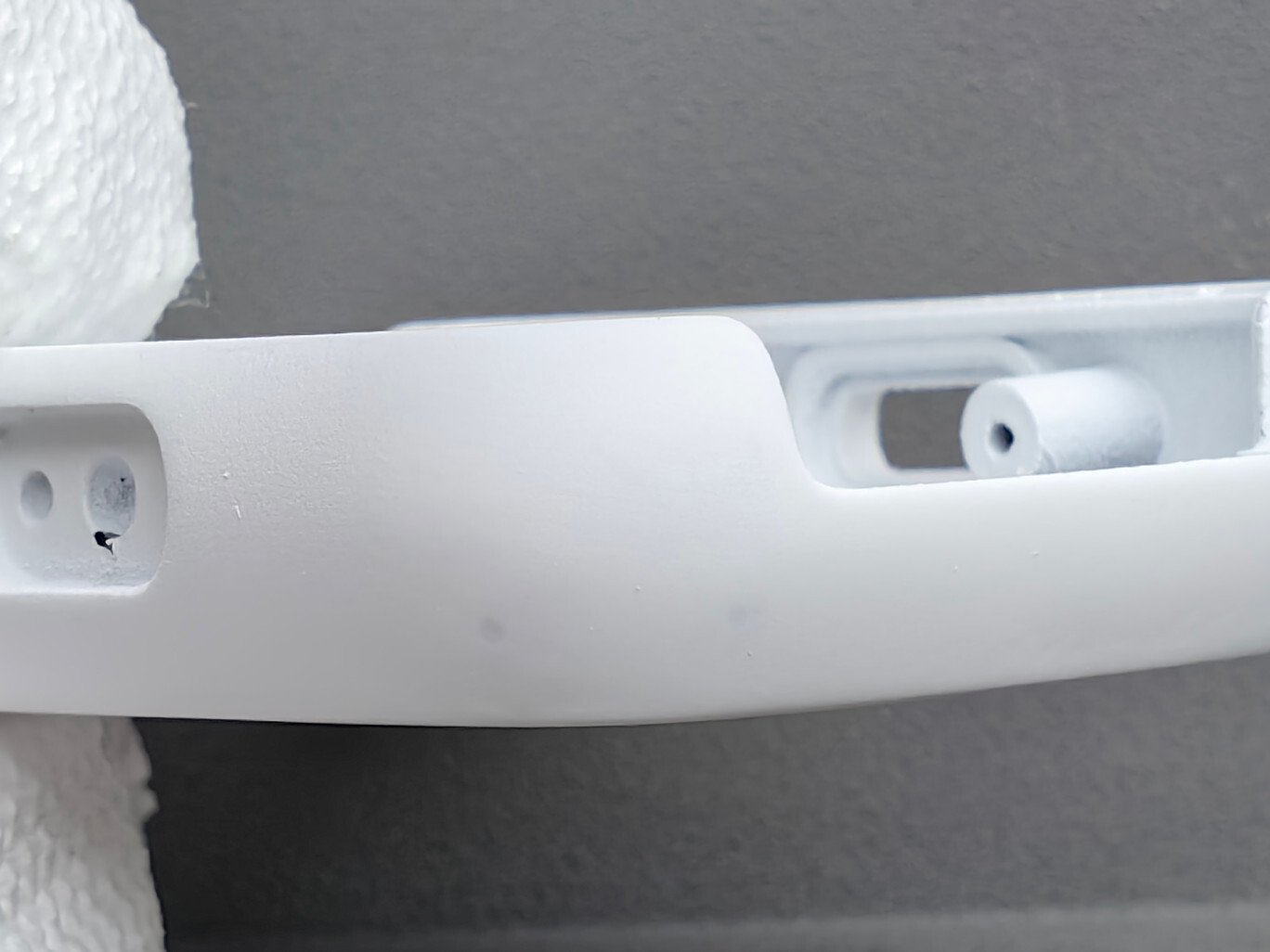 Close-up inspection of a white wearable housing showing a localized surface defect after prototype replication